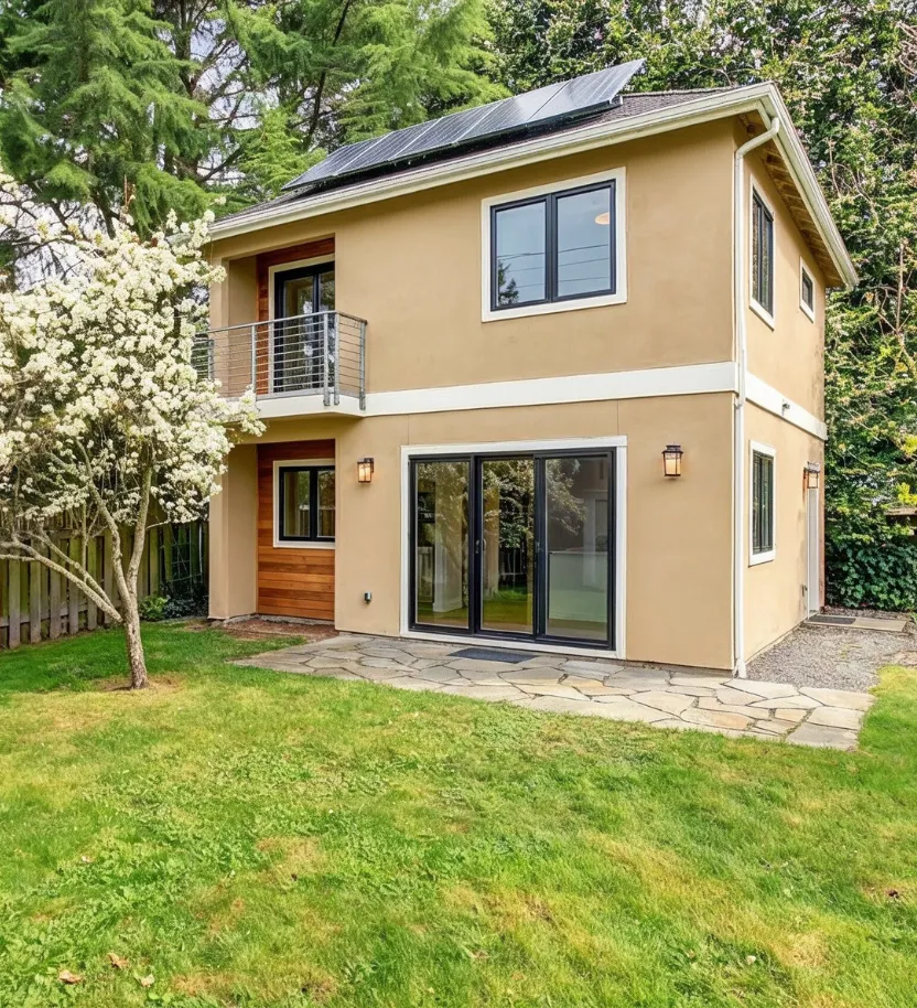 Two story backyard accessory dwelling unit with beige stucco exterior, balcony, and solar panels built by a Los Angeles ADU construction company